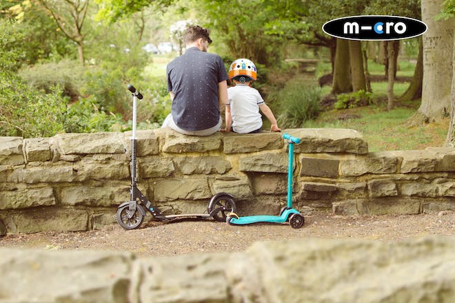 Man and boy sat on wall with micro scooter