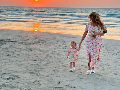 Stacey and daughters in matching dress in front of sunset at beach