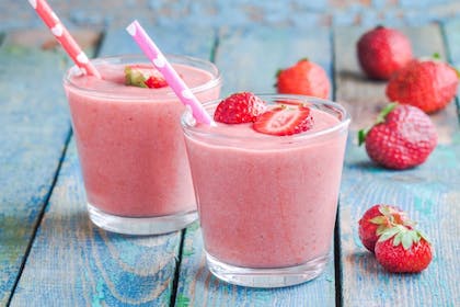 Two glasses of strawberry milkshake with straws