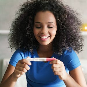 smiling woman holding pregnancy test